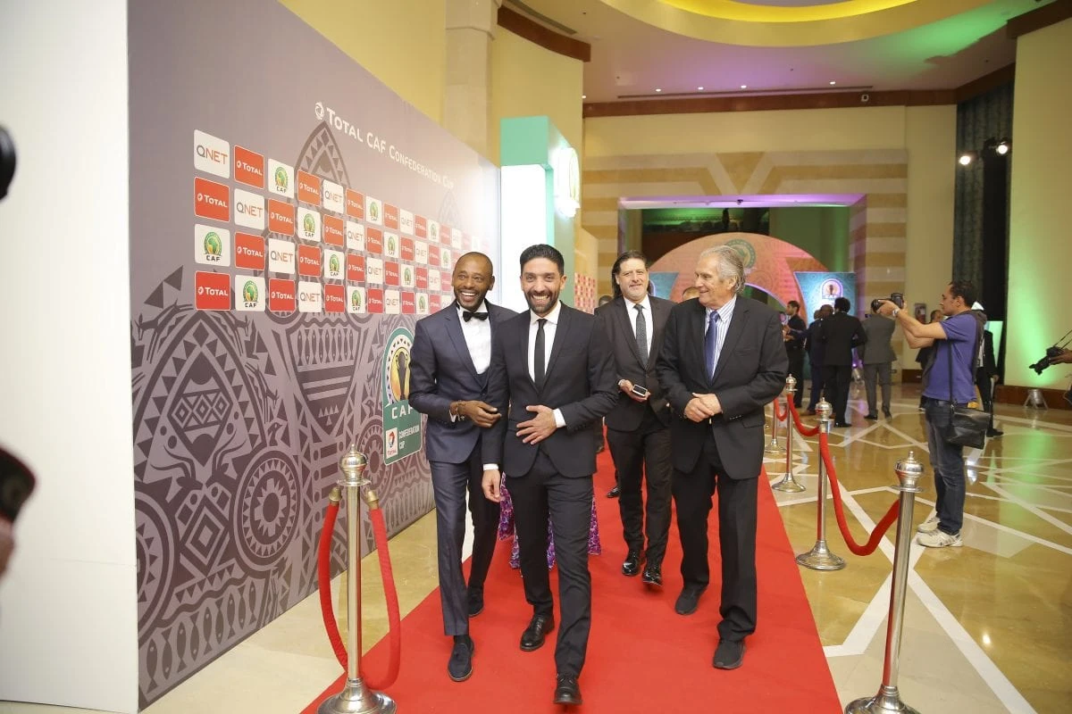 Qnet Shines Bright At Caf Draw, Signalling A Continuing Win-Win Sponsorship 2 QNET sponsored event in CAF, people in suits walking along the red carpet.