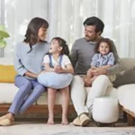 A family of four happily gathered on the living room couch, with a nearby HomePure ensuring clean and purified air.