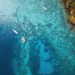 A stunning aerial perspective of a serene lagoon, featuring small fishing boats gracefully adrift on its tranquil surface.
