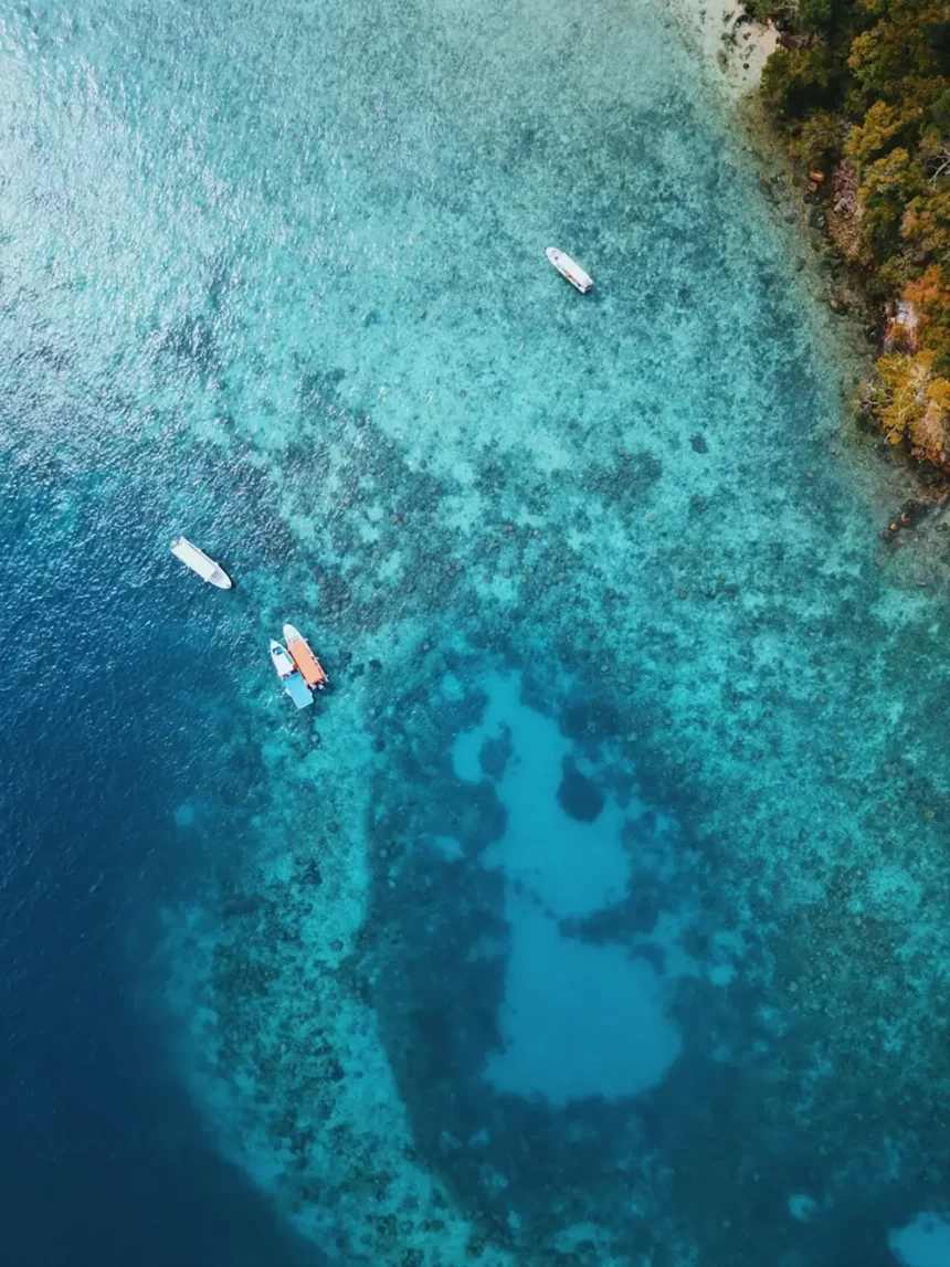 A stunning aerial perspective of a serene lagoon, featuring small fishing boats gracefully adrift on its tranquil surface.