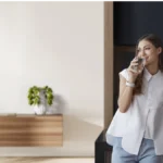 Woman standing next to homepure viva drinking water in kitchen