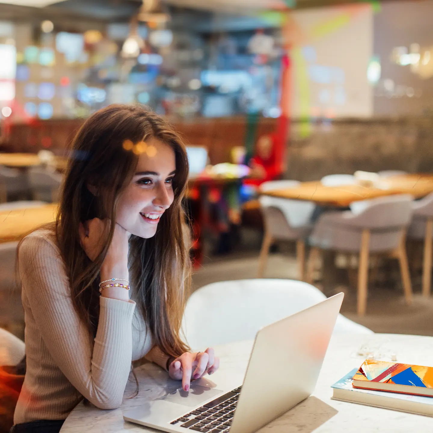 women sitting in a cafe on the computer smiling