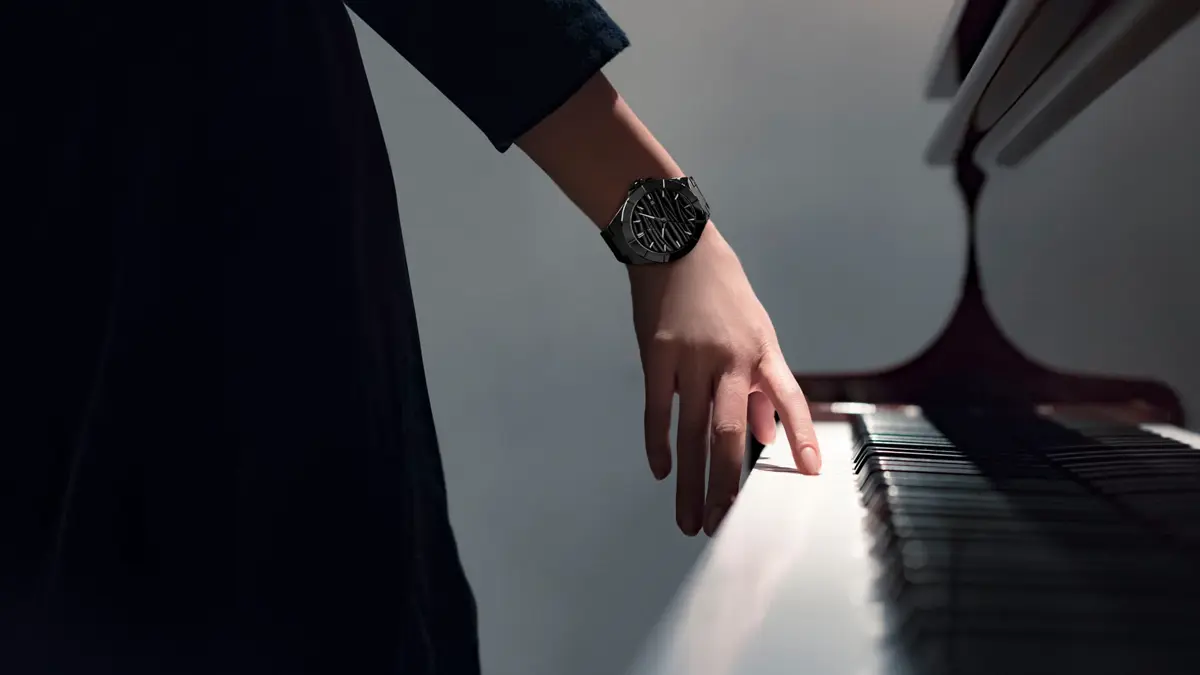 Woman's hand on the piano; there is a Bernhard H. Mayer Alto Ceramic watch on her wrist 