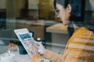 Caucasian girl engaging in hybrid learning with qLearn's management and leadership audio library on her tablet while she's at a cafe