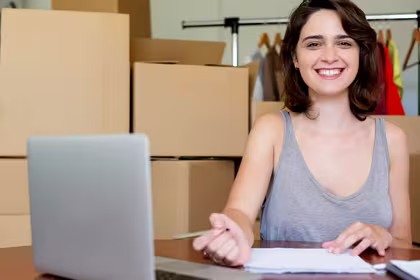 Girl smiling in front of boxes for her micro, small and medium-sized enterprise